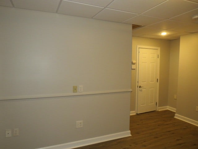 spare room featuring a paneled ceiling and dark wood-type flooring