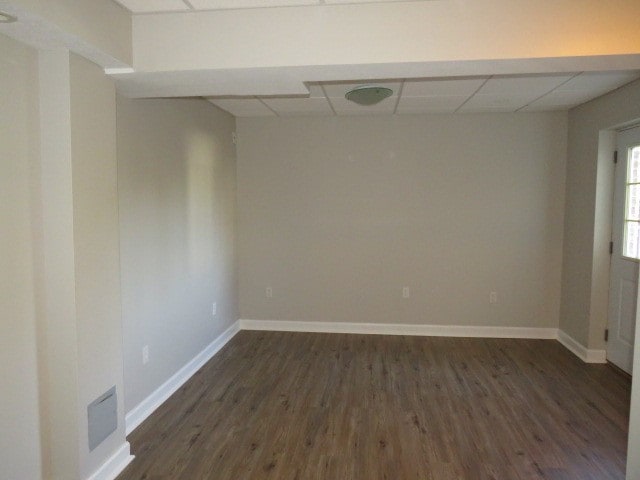 spare room with dark wood-type flooring and a drop ceiling