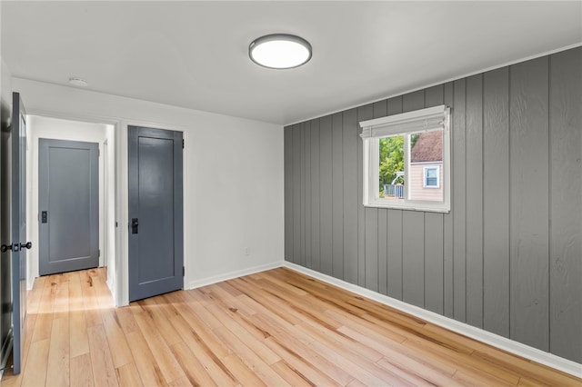 spare room with light hardwood / wood-style floors and wooden walls