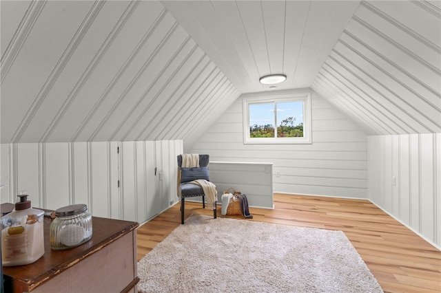 bonus room featuring light wood-type flooring, wood walls, and vaulted ceiling