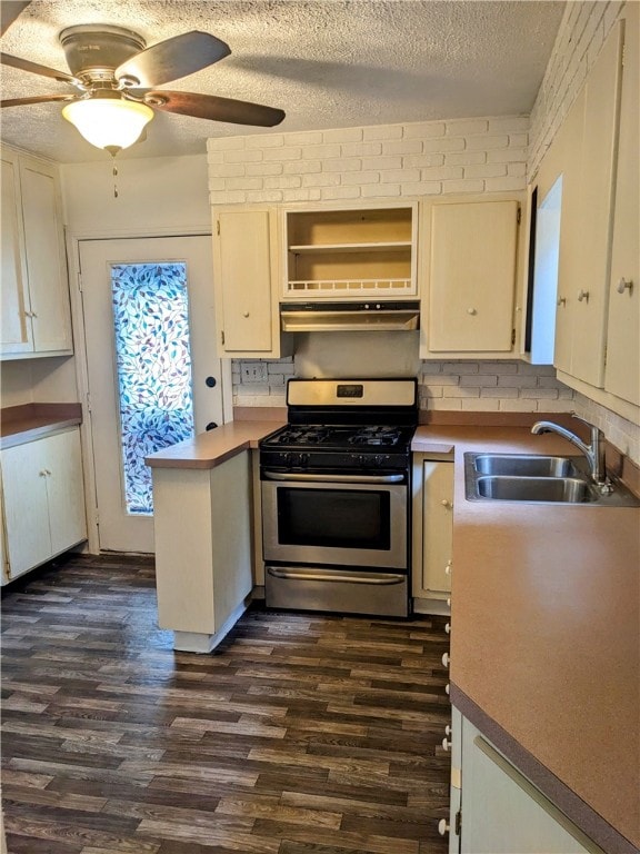 kitchen with ventilation hood, sink, stainless steel range with gas cooktop, dark hardwood / wood-style floors, and a textured ceiling