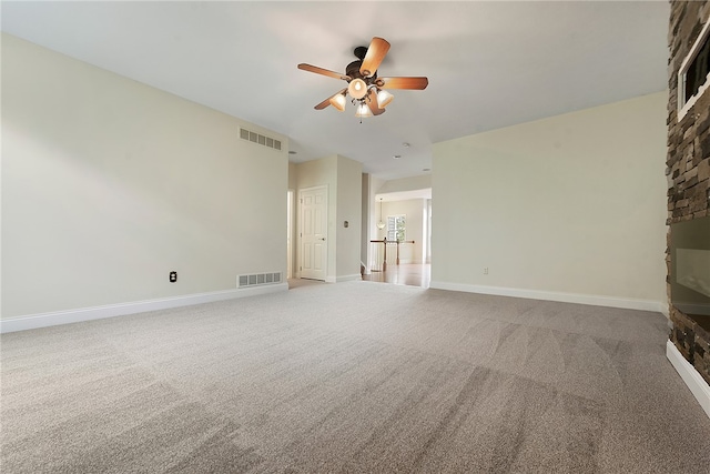 unfurnished room featuring a brick fireplace, carpet flooring, and ceiling fan