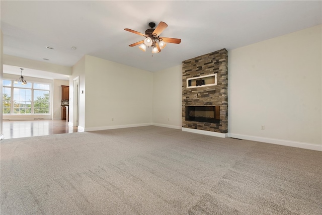 unfurnished living room with ceiling fan with notable chandelier, carpet, and a fireplace