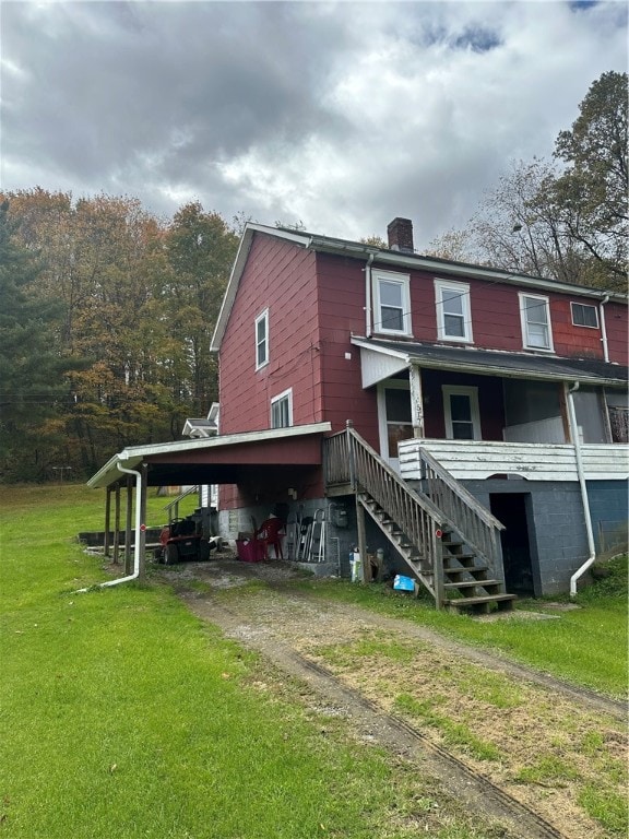 rear view of property featuring a yard and a carport