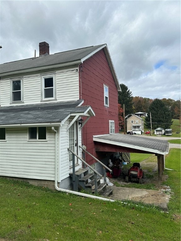 back of house featuring a carport and a yard