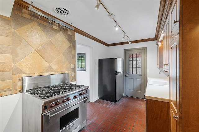 kitchen featuring rail lighting, sink, crown molding, appliances with stainless steel finishes, and backsplash