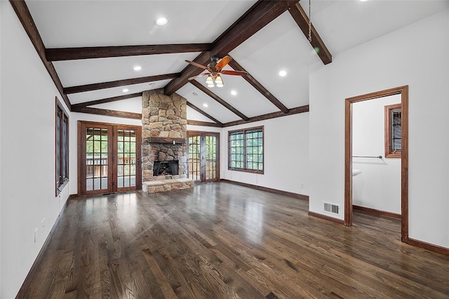 unfurnished living room featuring ceiling fan, beam ceiling, dark hardwood / wood-style floors, a stone fireplace, and french doors