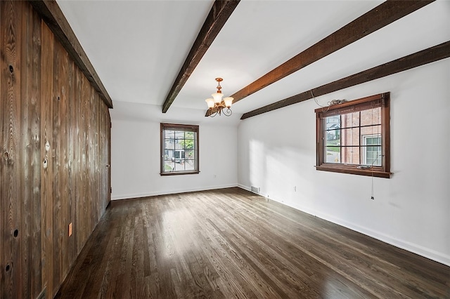 unfurnished room with a barn door, dark hardwood / wood-style floors, beamed ceiling, and an inviting chandelier