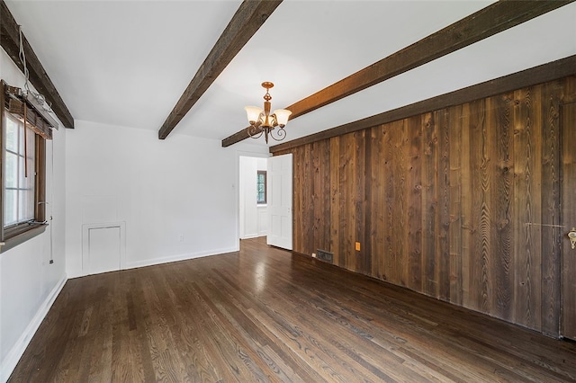 unfurnished living room featuring a notable chandelier, beamed ceiling, wooden walls, and dark hardwood / wood-style flooring