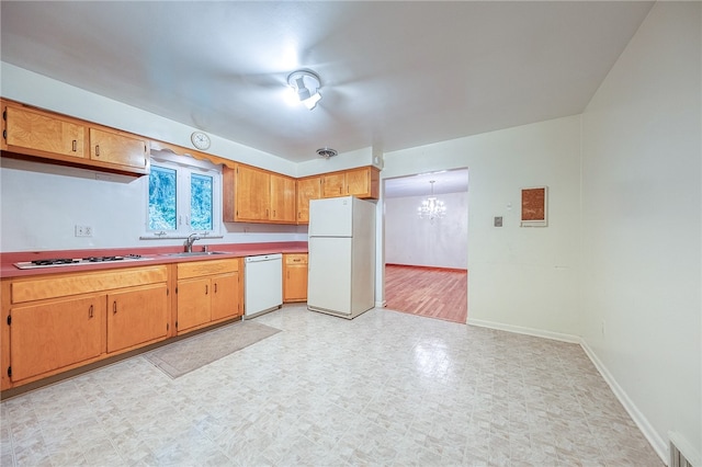 kitchen featuring a chandelier, sink, pendant lighting, and white appliances