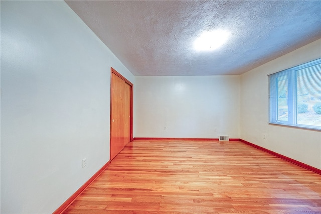 spare room with light hardwood / wood-style floors and a textured ceiling