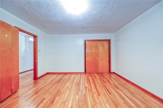 empty room featuring a textured ceiling and light hardwood / wood-style floors