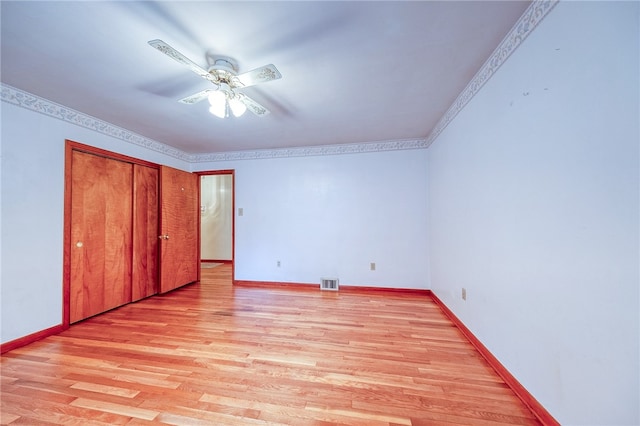 unfurnished bedroom with ornamental molding, a closet, light hardwood / wood-style floors, and ceiling fan