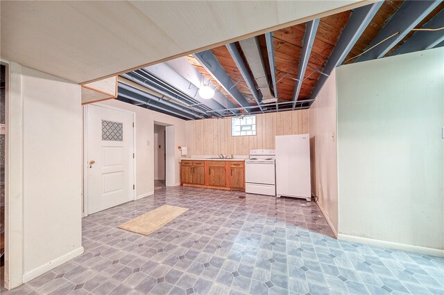 basement featuring white fridge and wood walls