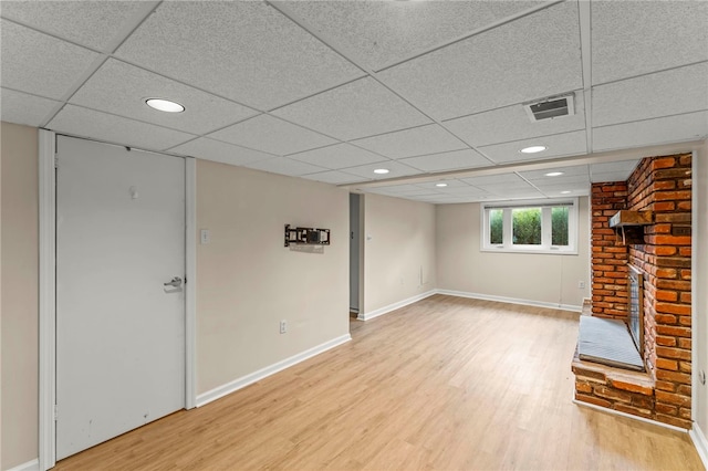 basement with a paneled ceiling, hardwood / wood-style floors, and a fireplace