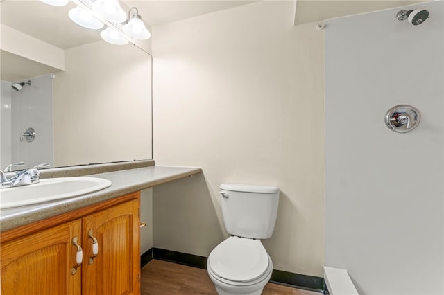 bathroom featuring wood-type flooring, vanity, a shower, and toilet