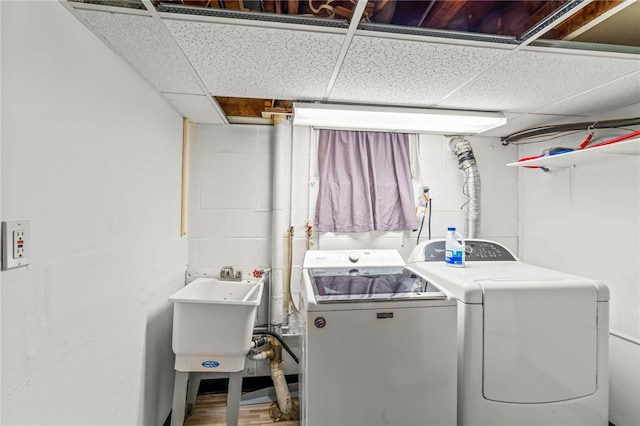 clothes washing area with independent washer and dryer, sink, and wood-type flooring