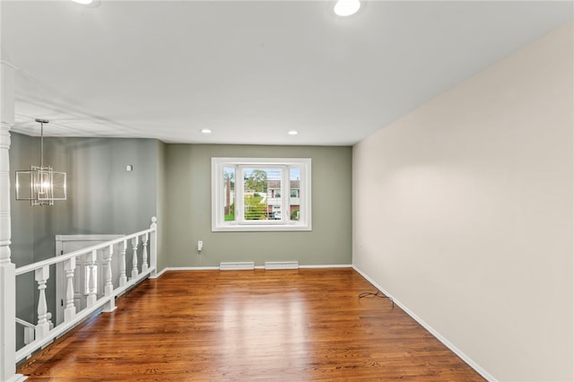 spare room with hardwood / wood-style flooring and a chandelier