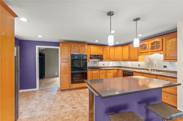 kitchen with black appliances, a center island, a breakfast bar, sink, and decorative light fixtures