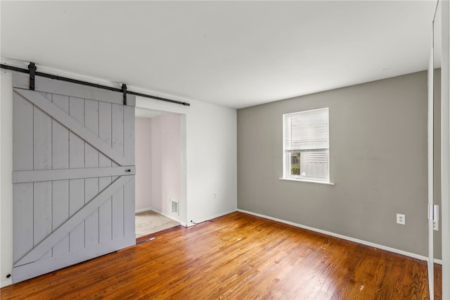 spare room with a barn door and light hardwood / wood-style flooring