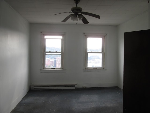 carpeted empty room with ceiling fan, a baseboard heating unit, and a healthy amount of sunlight