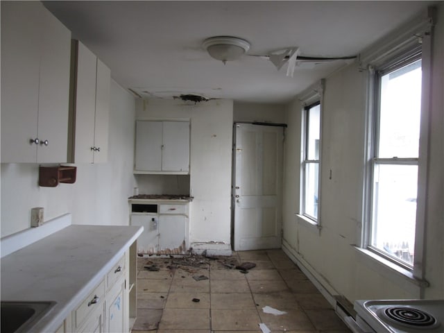 kitchen with a wealth of natural light, light tile patterned floors, and white cabinets