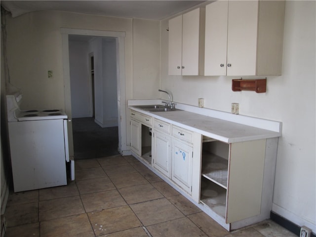 kitchen with light tile patterned floors, white range with electric cooktop, white cabinets, and sink