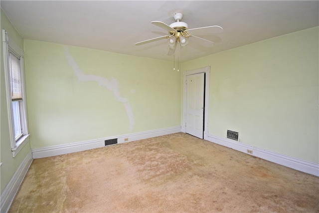 carpeted spare room featuring a wealth of natural light and ceiling fan