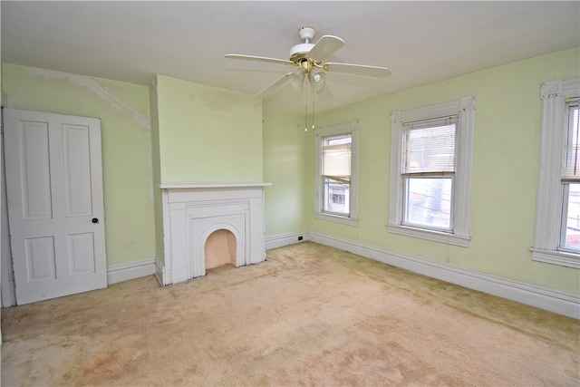 unfurnished living room with plenty of natural light, light colored carpet, and ceiling fan