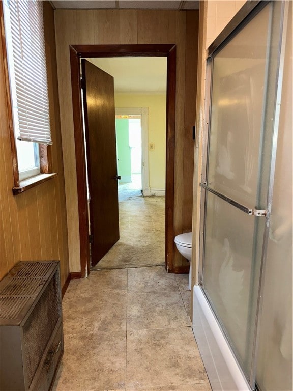 bathroom featuring wood walls, toilet, and plenty of natural light