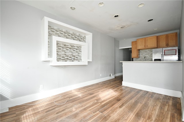 kitchen featuring decorative backsplash, stainless steel refrigerator, and hardwood / wood-style flooring