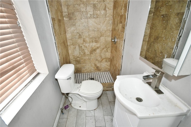 bathroom featuring a tile shower, toilet, and sink