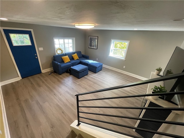 unfurnished living room featuring wood-type flooring, a textured ceiling, vaulted ceiling, and a wealth of natural light