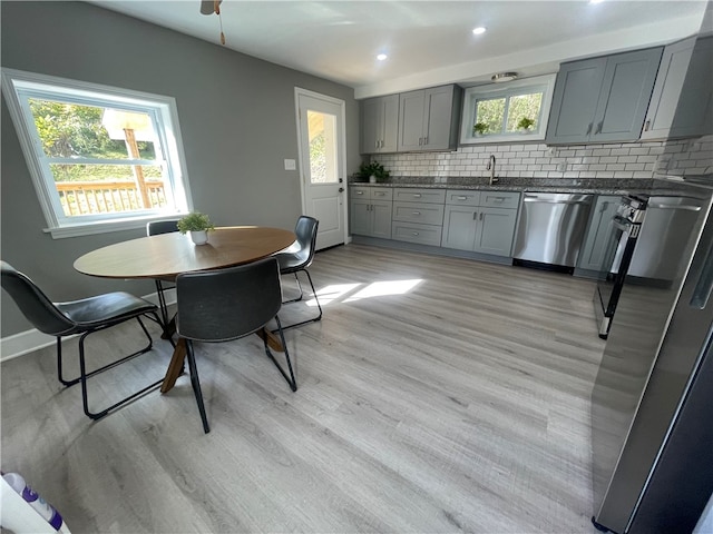 kitchen with dishwasher, light hardwood / wood-style flooring, backsplash, and gray cabinetry