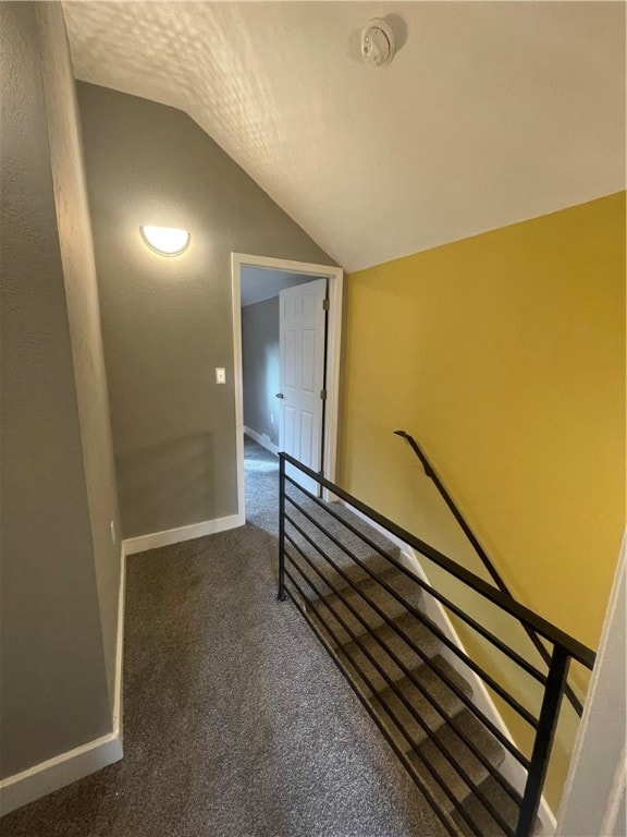 stairway featuring vaulted ceiling, carpet, and a textured ceiling