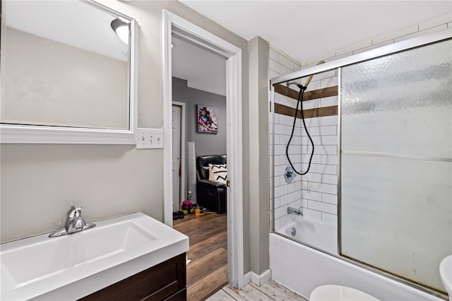 full bathroom featuring toilet, hardwood / wood-style flooring, bath / shower combo with glass door, and vanity