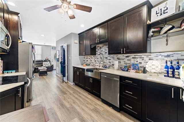 kitchen featuring dark brown cabinetry, sink, stainless steel appliances, light wood-type flooring, and decorative backsplash