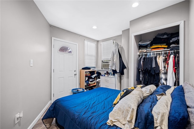 bedroom with wood-type flooring, cooling unit, and a closet