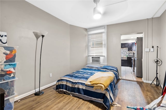 bedroom with light wood-type flooring and stainless steel refrigerator