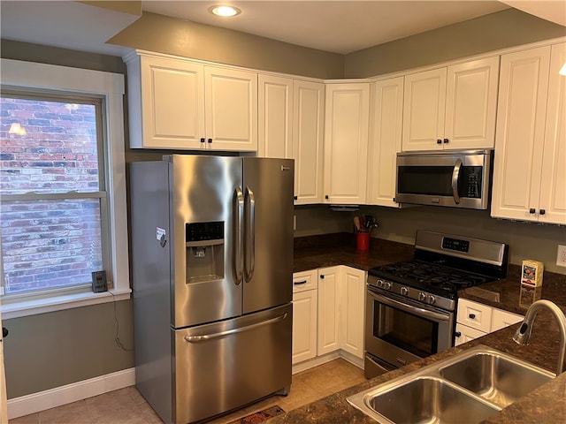 kitchen featuring white cabinetry, sink, light tile patterned floors, and stainless steel appliances