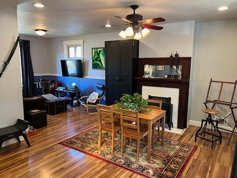 dining area featuring hardwood / wood-style floors, ceiling fan, and a fireplace