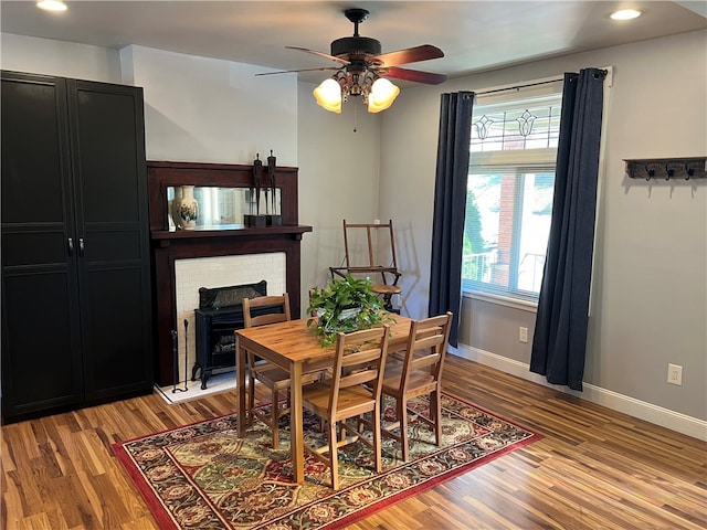 dining area featuring light wood-type flooring, a wood stove, and ceiling fan