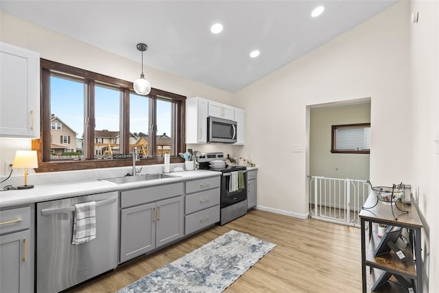 kitchen featuring pendant lighting, light hardwood / wood-style flooring, vaulted ceiling, sink, and appliances with stainless steel finishes