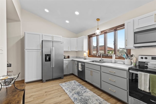 kitchen with white cabinets, lofted ceiling, gray cabinets, stainless steel appliances, and light hardwood / wood-style floors