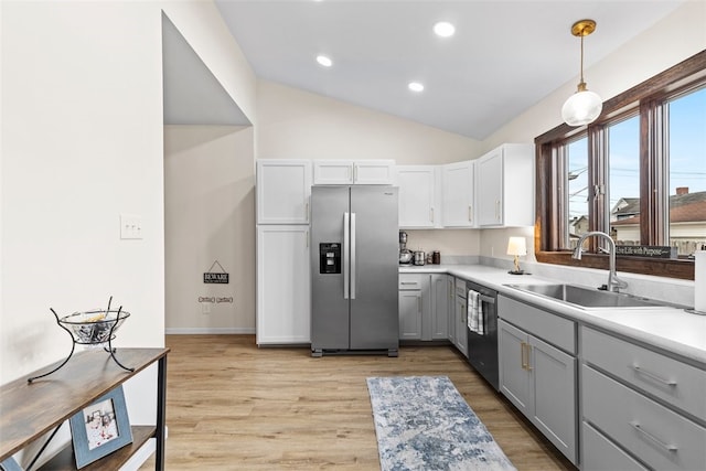 kitchen featuring sink, pendant lighting, vaulted ceiling, light hardwood / wood-style flooring, and appliances with stainless steel finishes