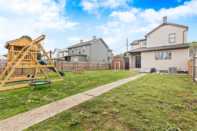 view of play area featuring a storage shed, a yard, and central air condition unit