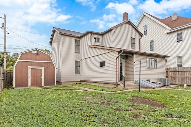 rear view of property with a yard, central AC, and a storage unit