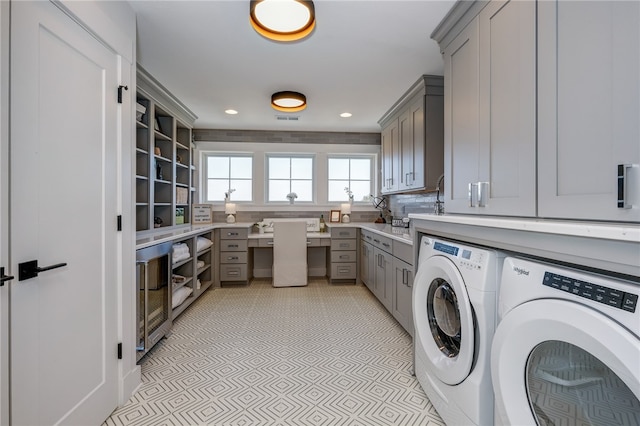 laundry area featuring light tile patterned flooring, wine cooler, washer and clothes dryer, and cabinets