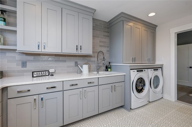 laundry room with washing machine and clothes dryer, cabinets, and sink