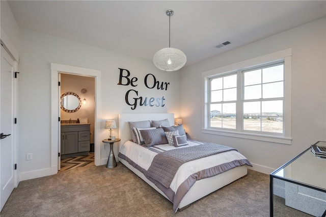 carpeted bedroom featuring ensuite bathroom and sink